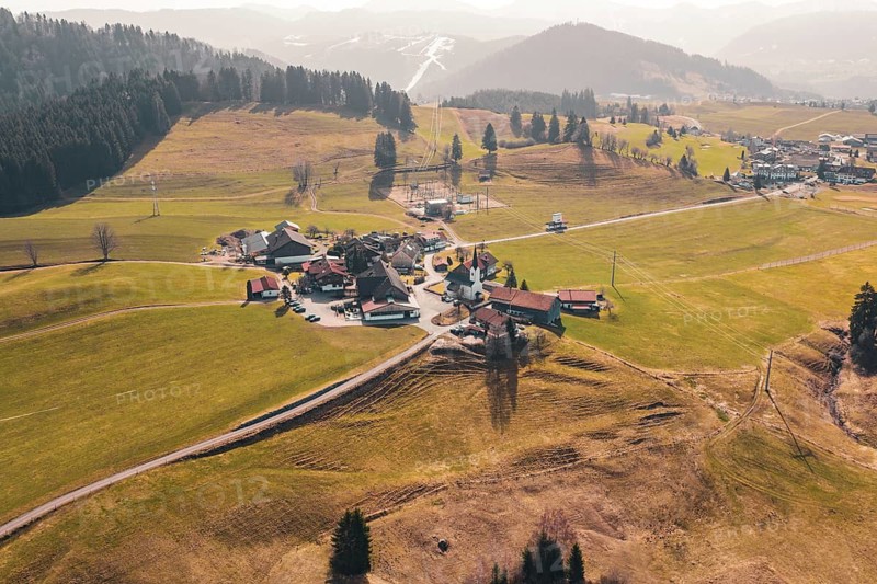 A village is surrounded by green meadows and gentle hills, surrounded by mountains, Oberreute, Allgäu, Germany