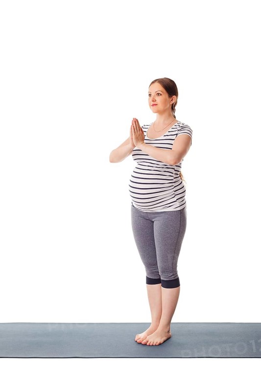 Pregnancy yoga exercise, pregnant woman doing yoga asana Tadasana Mountain pose with namaste isolated on white background