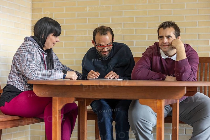 A supportive caregiver interacts with two residents at a mental health residence, sharing a moment of connection and engagement. The setting fosters inclusion, companionship, and emotional well-being