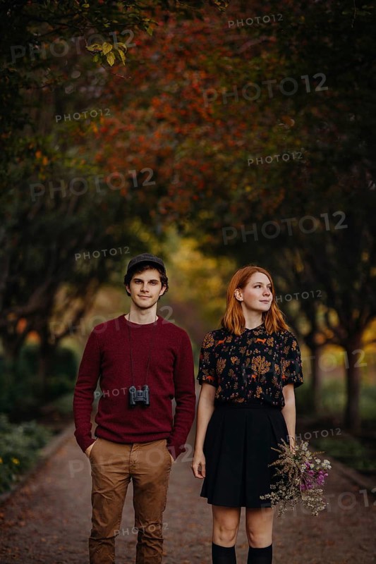A couple takes a leisurely stroll through a picturesque path in Quebec during autumn. The surrounding trees display stunning fall colors, creating a warm, inviting atmosphere
