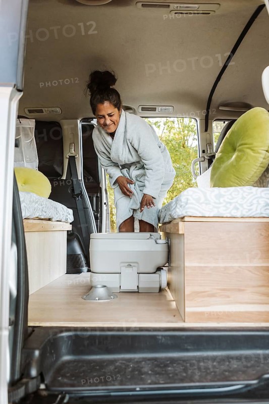 A woman enjoying her van life routine in New Zealand during autumn. She engages in everyday activities with a cozy setup, surrounded by nature's fall colors