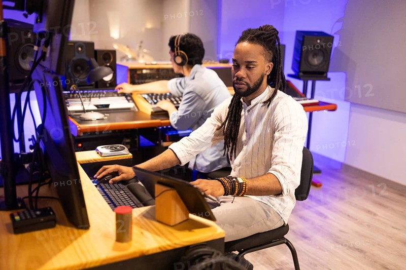 Two audio engineers focus intently on music production in a modern recording studio, surrounded by high-end equipment, creating a dynamic and creative atmosphere