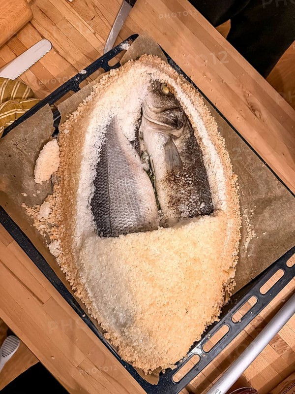Fish in salt crust with opened salt crust on a baking tray, prepared by yourself, food photography, Munich, Bavaria, Germany