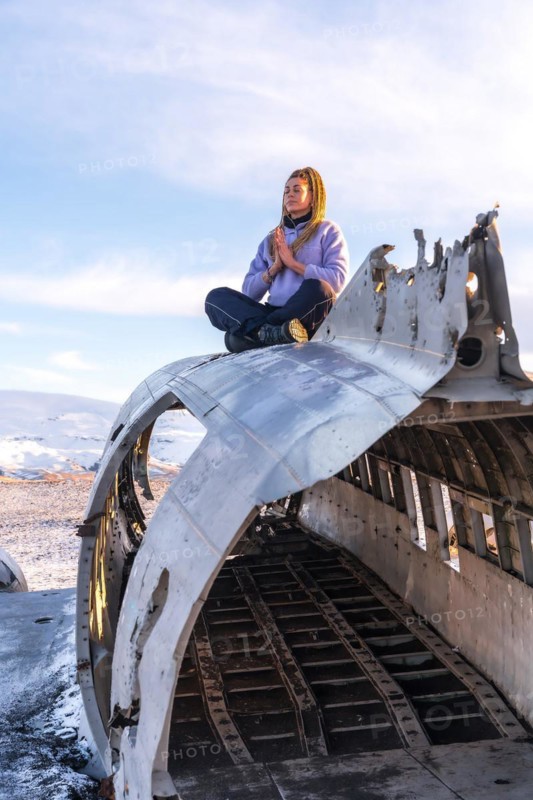 Woman sitting on the plane of Solheimasandur meditating in Iceland