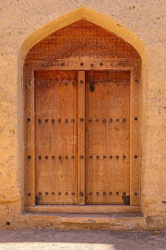 Decorated round arch entrance door in the largest preserved mud town in Oman, Al Bilaad, Al Bilaad Historical Village, Arabian Peninsula, Sultanate of Oman
