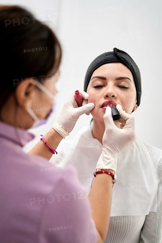 A beauty professional provides makeup application to a client in a modern aesthetic medicine clinic. The focus is on creating a fresh and polished look in a serene environment