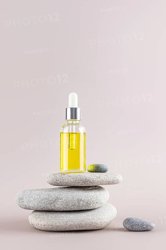 A soothing scene featuring a dropper bottle of yellow essential oil on stacked smooth stones, creating a zen-like ambiance Perfect for spa, wellness, and relaxation themes