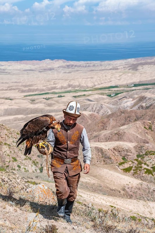 Traditional Kyrgyz eagle hunter hunting in the mountains in a dry landscape, near Kysyl-Suu, Issyk Kul, Kyrgyzstan