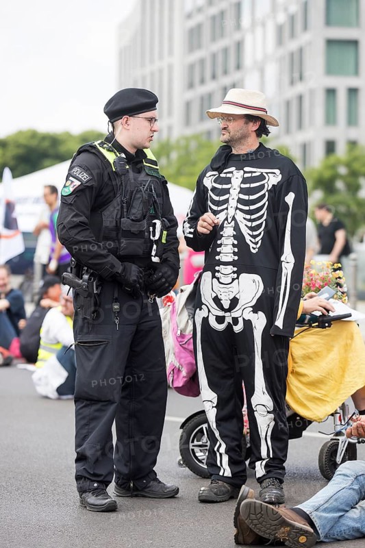 An activist from Wir hungern bis ihr ehrlich seid talks to a police officer during the occupation of Rahel-Deer-Straße in front of Berlin Central Station, Berlin, 25 May 2024
