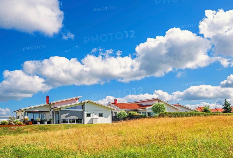 Modern residential house with slanted roofs, large windows situated by a green area a sunny summer day with a blue sky, Falköping, Sweden
