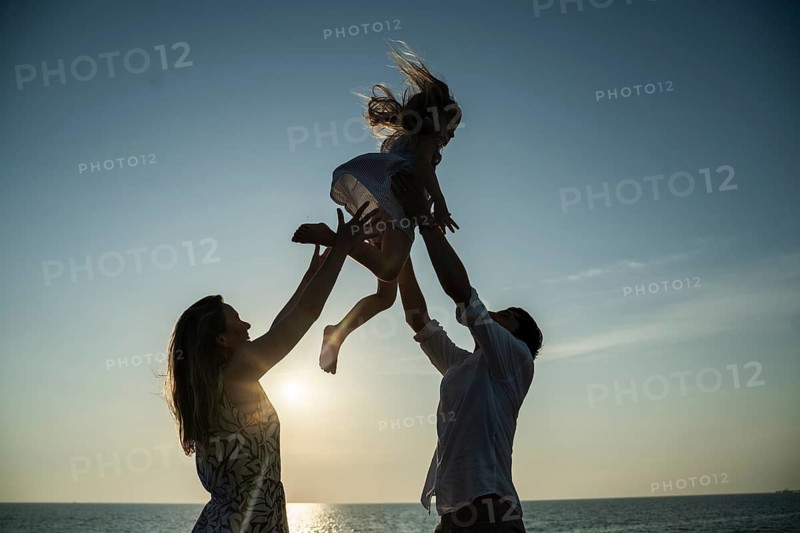 A family relishes precious moments on an Italian beach at sunset. With a serene horizon and playful joy, this captures a perfect scene of togetherness and happiness