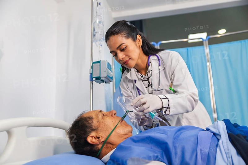 A compassionate doctor attentively assists a patient in a hospital room, ensuring proper care with medical equipment and oxygen support, highlighting dedication in healthcare settings