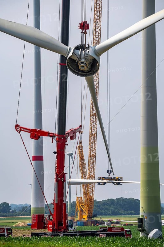 Dismantling of a wind power plant in a wind farm near Issum, 9 older wind turbines from the manufacturer Enercon (model series E-58), front, blades being dismantled, were in operation for over two decades, will be replaced by a total of four Enercon E-160 turbines, rear, assembly of the first blade, with a total output of 22 megawatts, Lower Rhine, North Rhine-Westphalia, Germany
