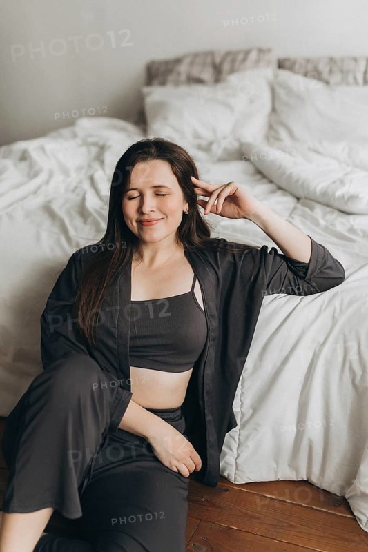 A woman in a cozy living space, dressed in a comfortable outfit, enjoying a peaceful moment. Her relaxed demeanor exudes wellness and balance, perfect for a health-focused concept