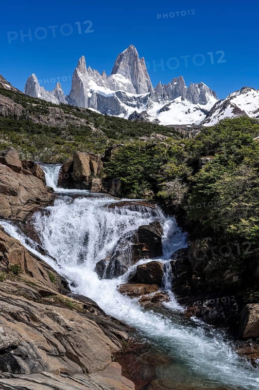 Chorrillo del Salto waterfall with view of Cerro Fitz Roy, snow-capped granite peaks against blue sky, Los Glaciares National Park, El Chaltén, Patagonia, Argentina