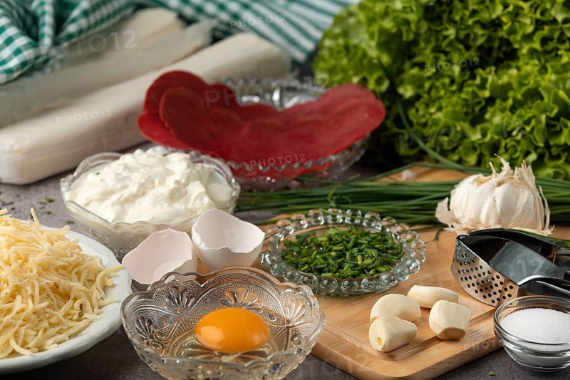 Ingredients, including puff pastry, egg, lettuce, cheese, chives, and fresh garlic
