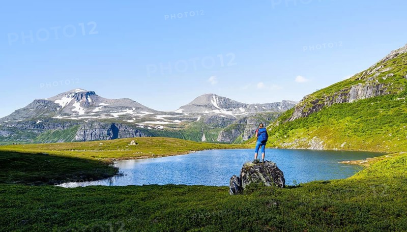 Female hiker standing on a rock in front of a mountain landscape, small lake in the Flatvaddalen high valley, side valley of Innerdalen, Sunndal, Møre og Romsdal, Vestlandet, Norway