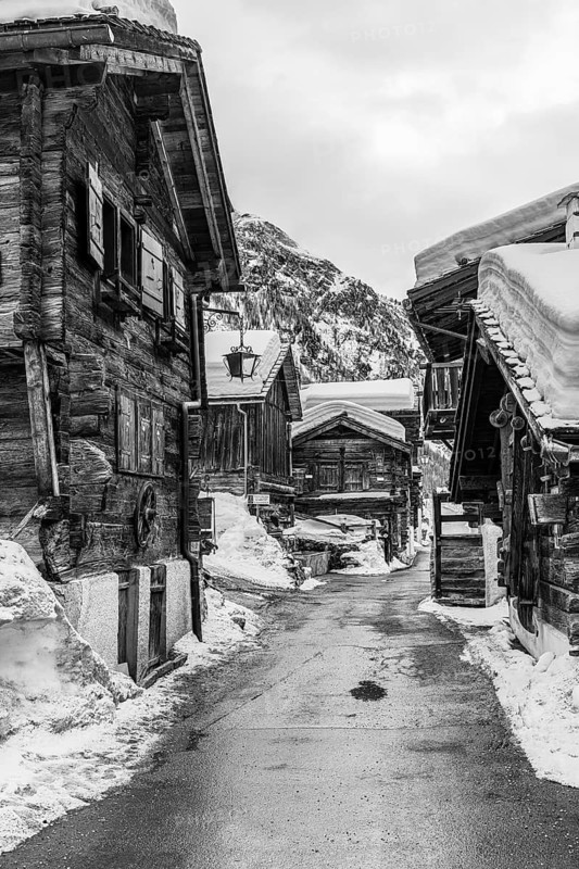 Street with historic old snow-covered wooden houses, black and white photo, mountain village Zinal, Val d'Anniviers, Valais Alps, Canton Valais, Switzerland