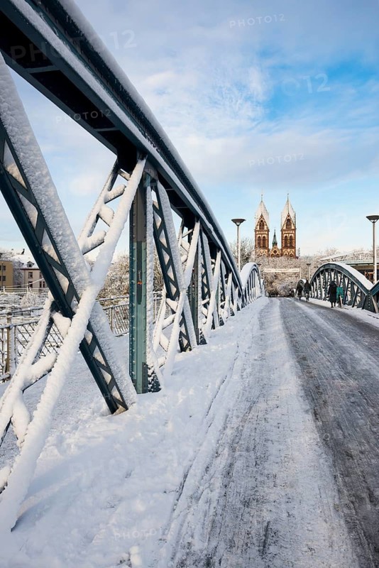 Bridge with snow and ice and cyclists, Blue Bridge and Stühlinger Church, Freiburg im Breisgau, Black Forest, Baden-Württemberg, Germany