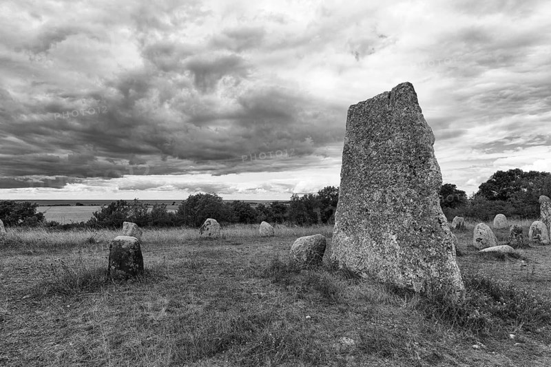 Granite block, burial ground from the Iron Age and Viking Age, stone rows, shipwrecking, barren limestone landscape, Stora Alvaret, UNESCO World Heritage Site, agricultural landscape in South Öland, dramatic cloudy sky, monochrome, Gettlinge, Südoeland, Öland island, Kalmar län, Sweden
