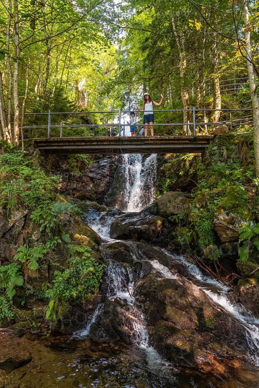 A mother and her son waving on a bridge at the Todtnau waterfall in the Black Forest in Germany