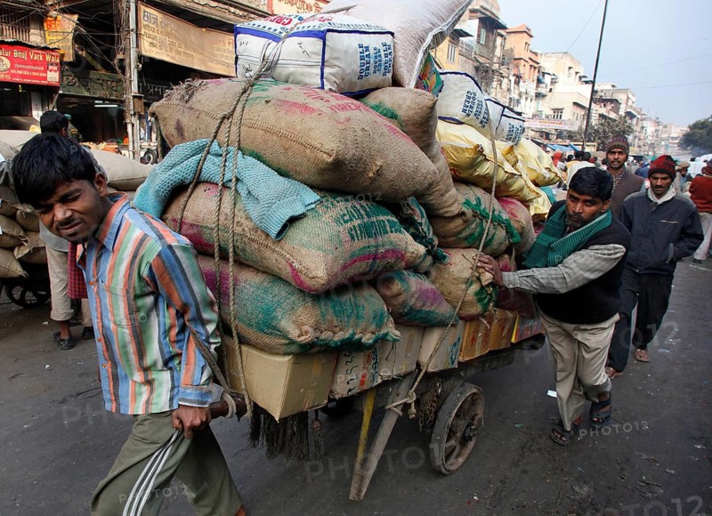 New Delhi, India, 14.01.10 - Two men push a trailer loaded with bags, India