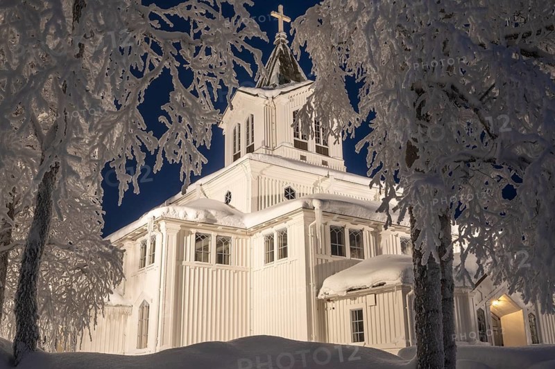 Illuminated wooden church with frost-covered birches, Gällivare, Norrbotten, Lapland, Sweden, December 2023