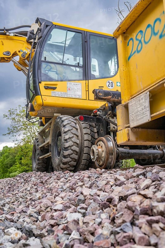 Close-up of a large yellow construction machine on a building site with large tyres and gravel, track construction Hermann Hesse Bahn, Calw, Black Forest, Germany
