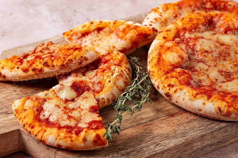 Four pizzetta Margaritas, on a cutting board, on a light gray surface, top view