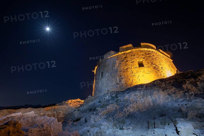 A captivating view of a historic stone tower on the Costa Blanca, beautifully illuminated at night with a bright starry sky above, creating a dramatic Mediterranean landscape