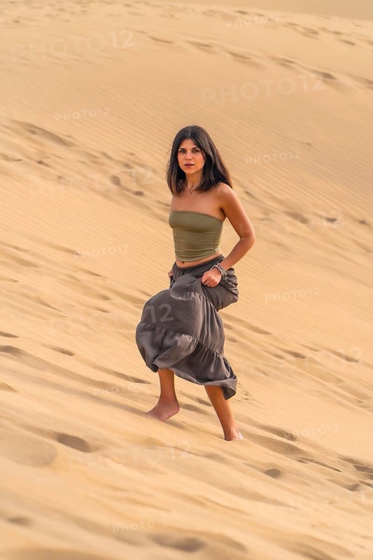 Young woman walking barefoot on the maspalomas dunes in gran canaria, enjoying the desert landscape