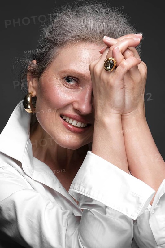 Portrait of a beautiful elderly woman in a white shirt with classic makeup and gray hair