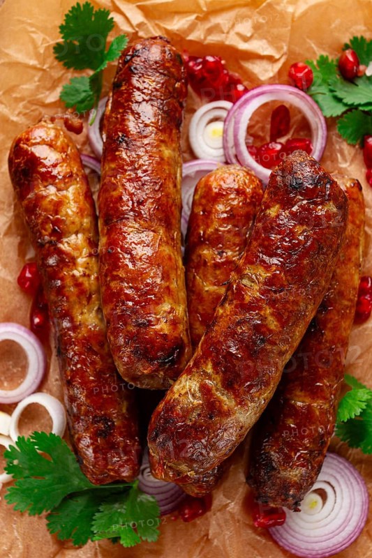 Fried kupaty on parchment, with red onion and pomegranate, kupaty, Georgian cuisine