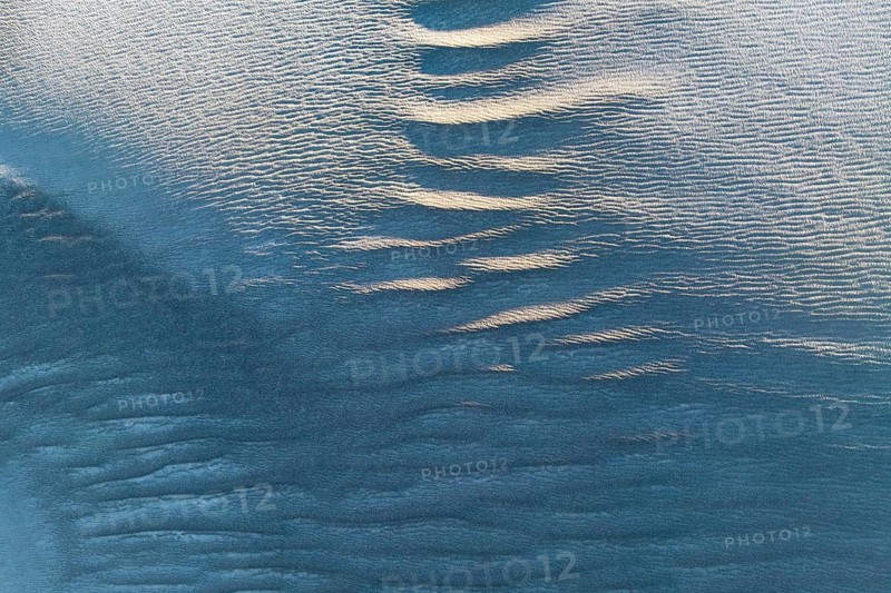 Rippling sand textures in La Puna desert capture the essence of nature's artistry. Soft light and shadows highlight intricate patterns created by wind and time in sunlit dunes