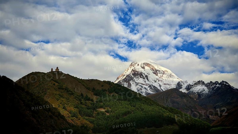 Snowy mountain peak, Kazbek, at sunset, Gergeti church on hill in the foreground, Stepantsminda, Caucasus, Georgia
