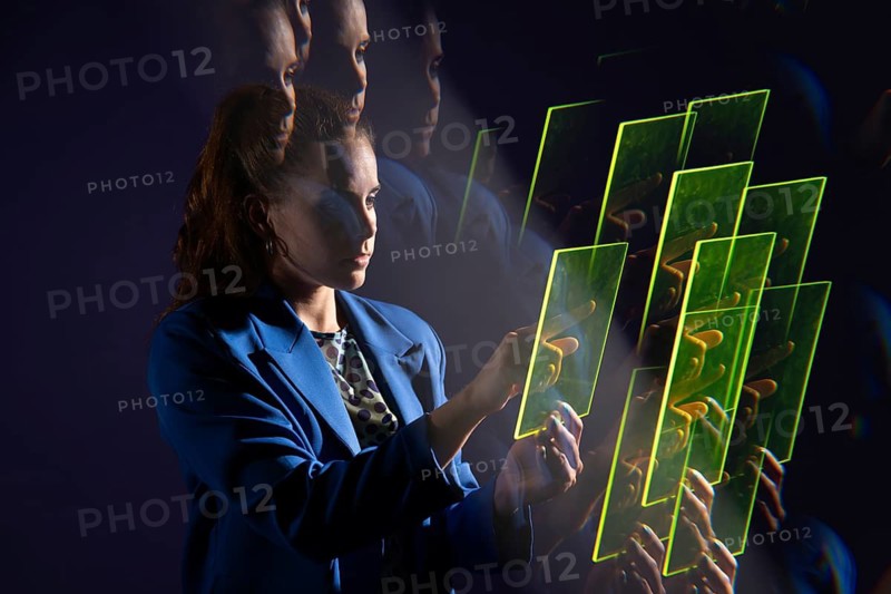 A young woman interacts with a series of transparent digital screens, symbolizing advanced technology and innovation. The vivid display suggests futuristic possibilities