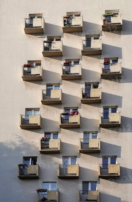 Facade of a residential building with balconies and long shadows on a sunny wall in a beautiful, uniform pattern, Szczecin, Poland