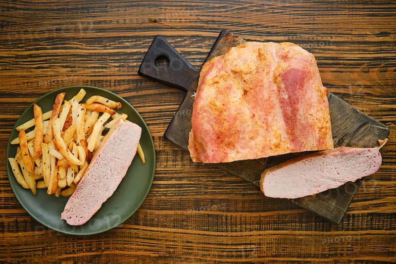 A plate holds crispy fries next to a wooden board with sliced meat. The setting is a simple diner during lunch hours. The table has a rustic look with warm tones