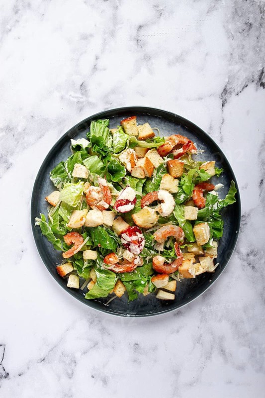 Caesar salad, with shrimp, on a marble background, top view, no people