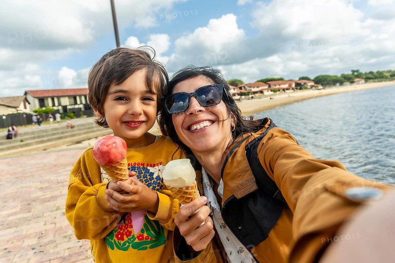 Mother and son smiling for a seaside selfie, enjoying ice cream cones during a sunny summer holiday in vieux boucau les bains, francewarm family bonding and joy