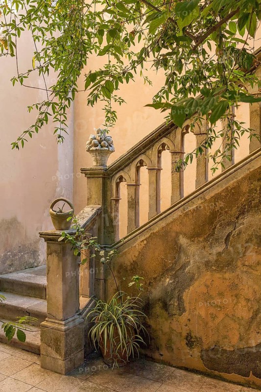 Weathered stone staircase with sturdy railings and plants, surrounded by nature and antique charm, Taormina, Sicily, Italy