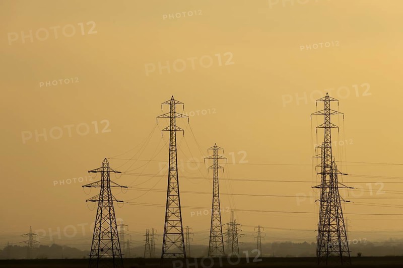Electricity pylons and power lines silhouette at sunset, England, United Kingdom
