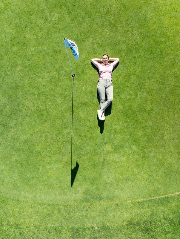 Woman lying on the green at the La Noria Golf Resort. Aerial view. Drone shot. Málaga province, Andalusia, Spain