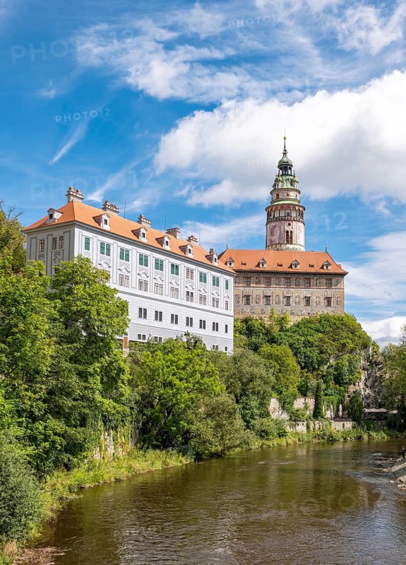 View of the Ceský Krumlov Castle with tower, colorful facade buildings, Vltava River, and greenery on a sunny day, Cesky Krumlov, Czech Republic