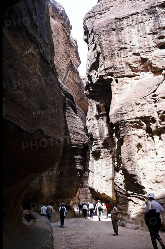Tourists walking through a narrow passageway (siq) to the entrance of the archaeological site in Petra, Jordan (1998)