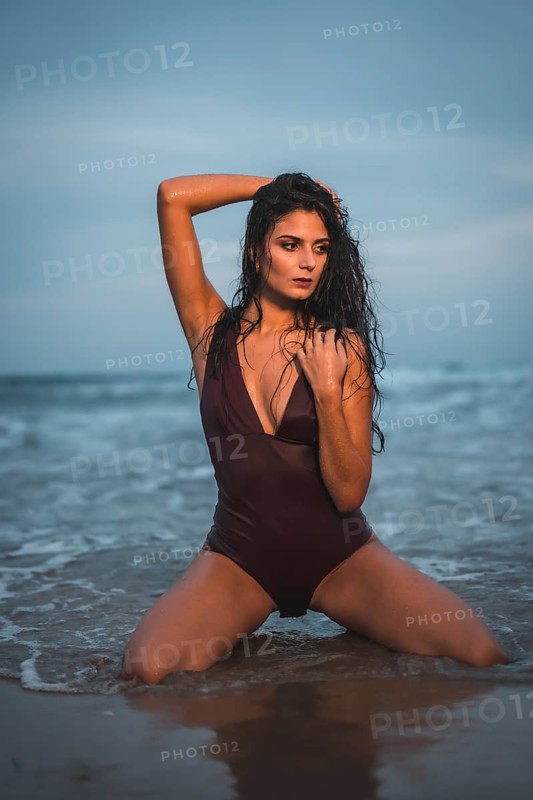 Sensual gaze of a Caucasian brunette in a maroon swimsuit, on the beach enjoying the holidays in the water