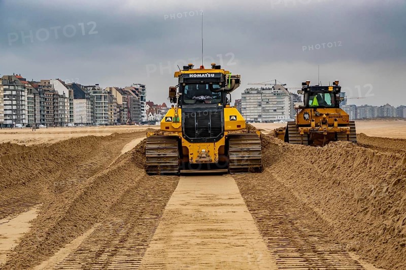 Bulldozers when distributing sand on the beach in the town of Knokke-Heist, part of coastal protection and beach maintenance, due to floods, erosion and sea level rise, the sand on the beach is repeatedly washed into the sea, in winter the sand from the seabed is washed back onto the beach with suction vessels, the excavators and levelers then distribute the sand back on the beach to eliminate the difference in height so as to bathe To make the beach usable again for the next season
