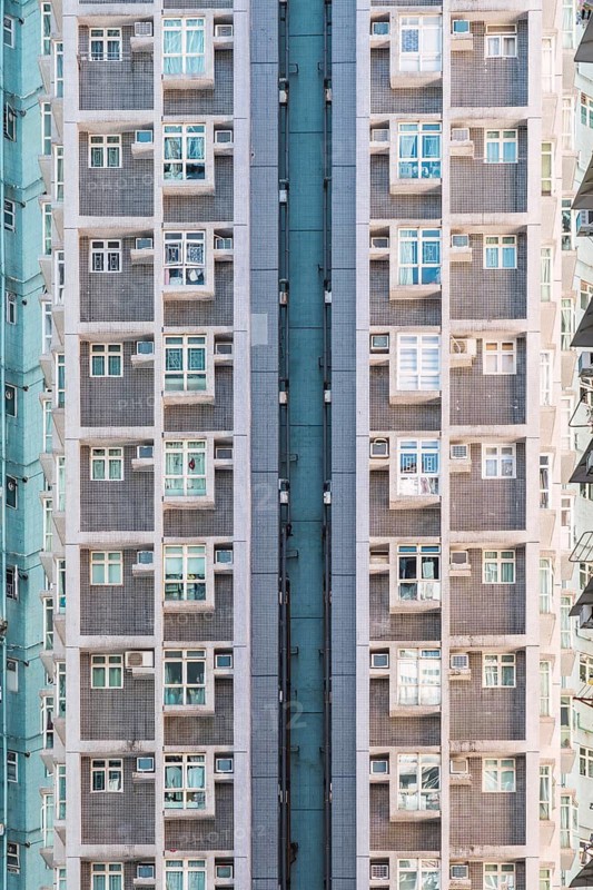 Tall residential building in Hong Kong demonstrates urban density and architecture. The facade features numerous windows and balconies, illustrating modern city living dynamics