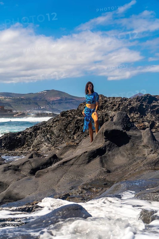 Tourist posing on volcanic rocks at the beach in arucas, gran canaria, canary islands, spain, enjoying summer holidays