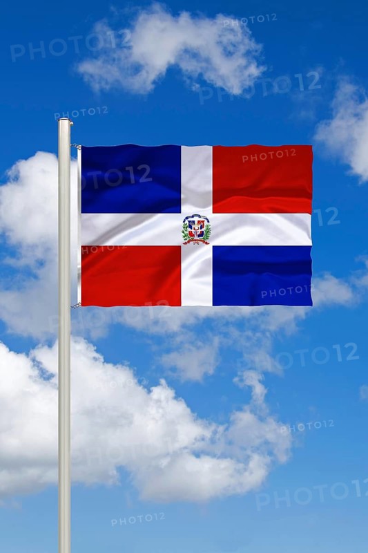 National flag of the Dominican Republic, island of Hispaniola, in front of cumulus clouds and blue sky, studio